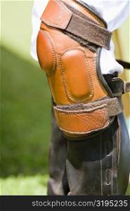 Close-up of a person&acute;s legs wearing riding boots and a kneepad