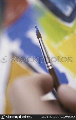 Close-up of a person holding a paintbrush