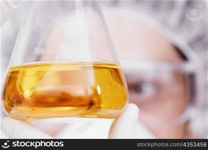 Close-up of a person looking at liquid in a conical flask