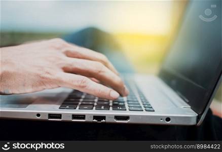 Close up of a person&rsquo;s hands on the laptop keyboard outdoors, Close-up of a man&rsquo;s hands working on his laptop. Side view of hands working on laptop