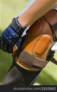 Close-up of a person tying a riding boot