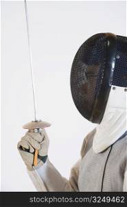 Close-up of a person wearing a fencing mask and holding a fencing foil