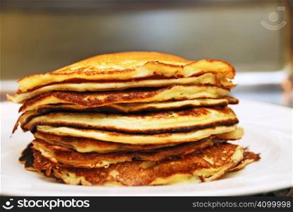 Close up of a pile of pancakes served on a white plate.