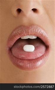Close-up of a pill on a young woman&acute;s tongue