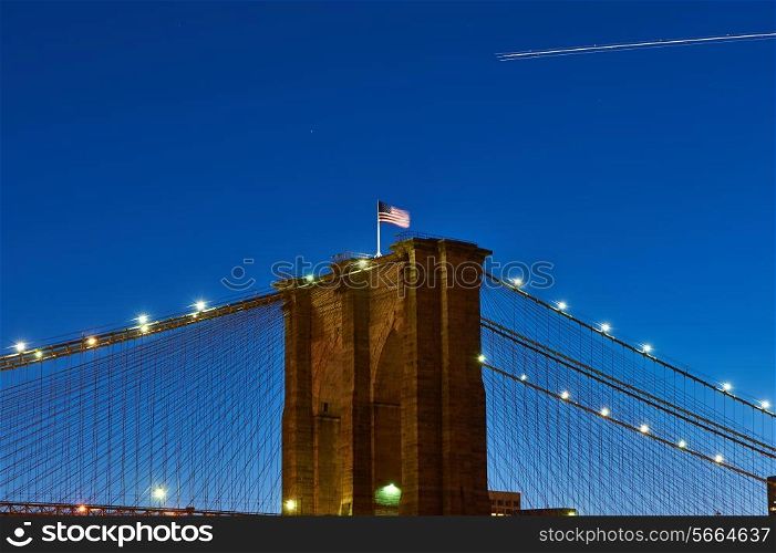 Close up of a pillar of the Brooklyn bridge with flag at night, New York City, USA