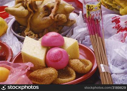 Close-up of a plate of sweets with a bundle of incense sticks