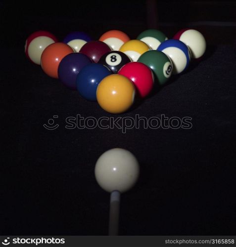 Close-up of a pool cue hitting a cue ball on a pool table