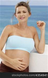 Close-up of a pregnant mid adult woman leaning against a wall with her hand on her abdomen