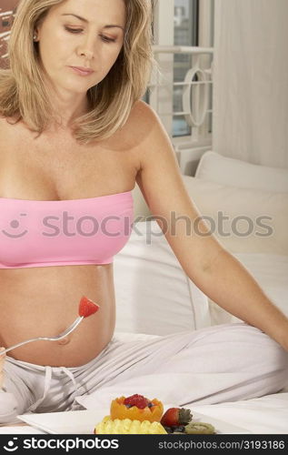 Close-up of a pregnant woman holding a strawberry on a fork