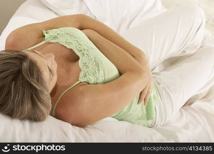 Close-up of a pregnant woman lying on the bed touching her abdomen