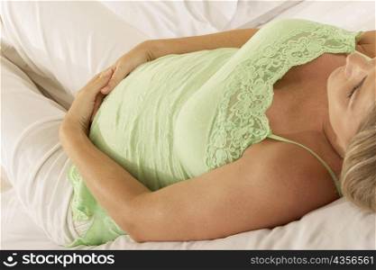Close-up of a pregnant woman lying on the bed touching her abdomen