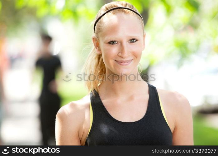 Close-up of a pretty woman in sports wear with friend in the background