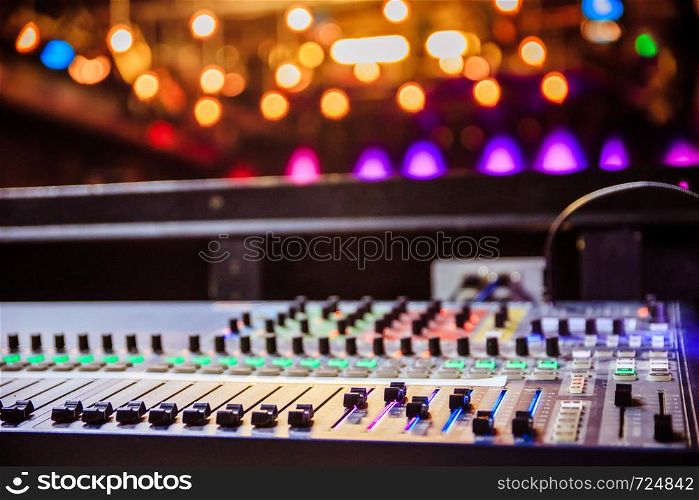 Close up of a professional recording mixer desk, concert with lights in the blurry background