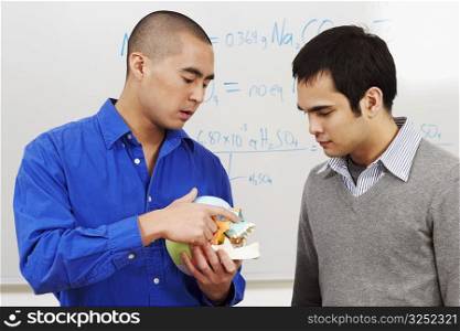 Close-up of a professor holding a human skull in front of his student in a classroom