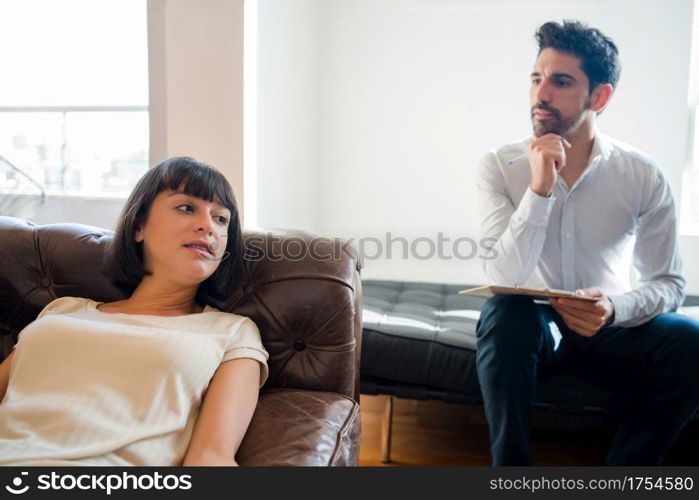 Close-up of a psychologist taking notes on clipboard and listening his patient during therapy session.. Psychology and mental health concept.