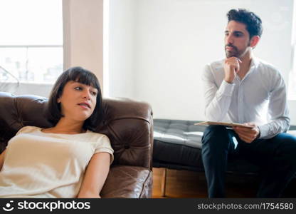 Close-up of a psychologist taking notes on clipboard and listening his patient during therapy session.. Psychology and mental health concept.