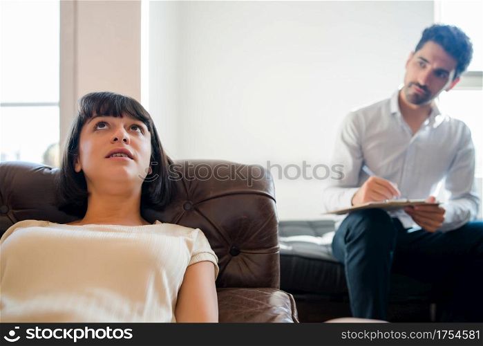 Close-up of a psychologist taking notes on clipboard and listening his patient during therapy session.. Psychology and mental health concept.
