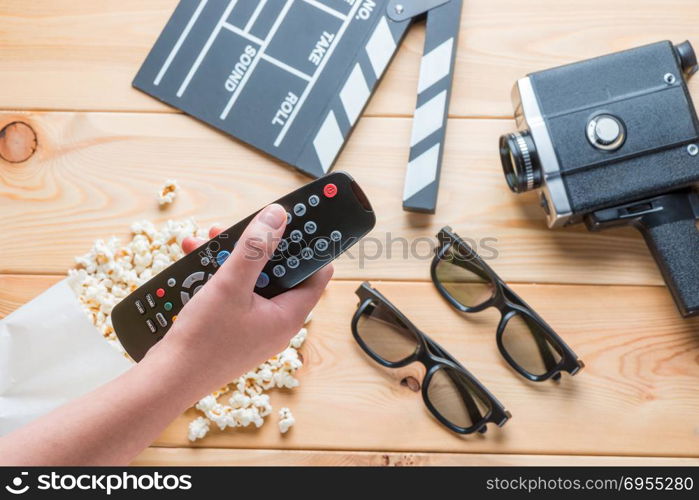 close-up of a remote from a TV set in a female hand against a background of a film industry object