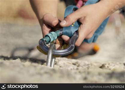 Close-up of a rock climber concording a carabiner with a hook