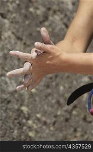 Close-up of a rock climber rubbing chalk powder on her hands
