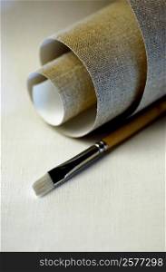 Close-up of a roll of canvas and a paintbrush