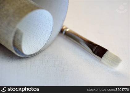 Close-up of a roll of canvas and a paintbrush