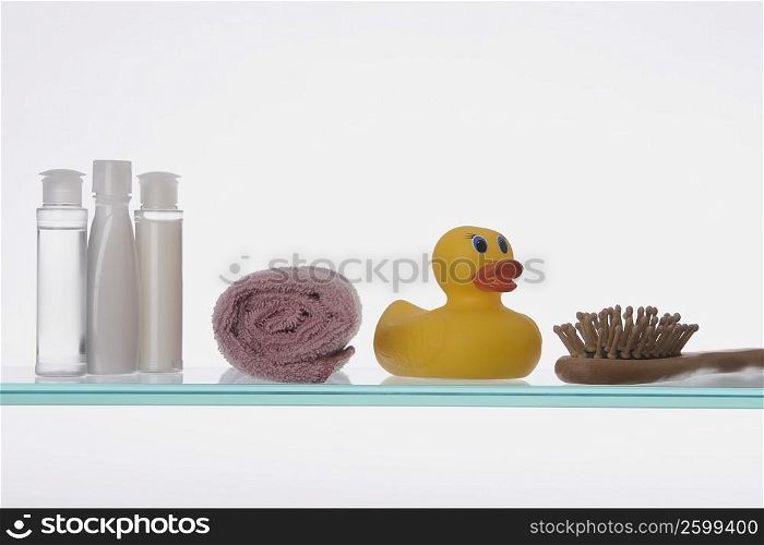 Close-up of a rubber duck with toiletries on a glass shelf
