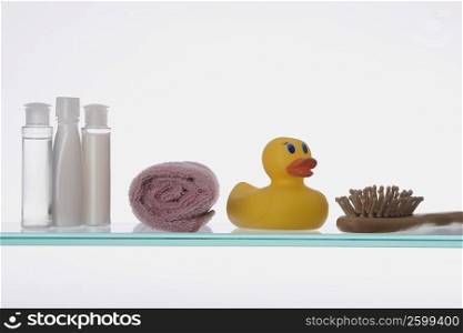 Close-up of a rubber duck with toiletries on a glass shelf
