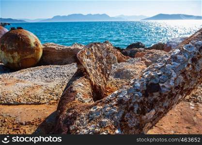 Close-up of a rusty anchor on the shore at Aegina island harbour in Greece