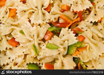 Close up of a salad with farfalle pasta, green and red bell peppers and Italian seasonings.