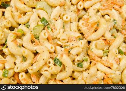 Close up of a salad with macaroni pasta, green onions, celery and carrots.