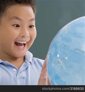 Close-up of a schoolboy looking at a globe and laughing
