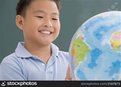 Close-up of a schoolboy looking at a globe in a classroom