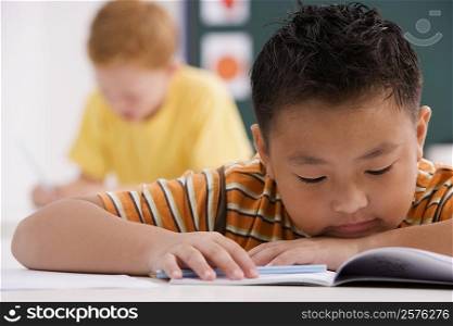 Close-up of a schoolboy reading a book in a classroom
