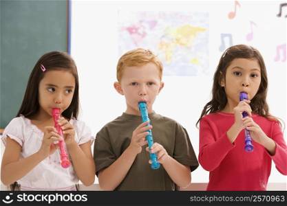 Close-up of a schoolboy with two schoolgirls playing flutes