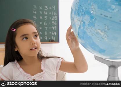 Close-up of a schoolgirl looking at a globe in a classroom