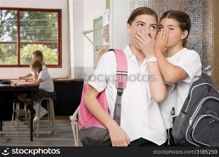 Close-up of a schoolgirl whispering to another schoolgirl