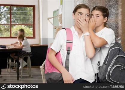 Close-up of a schoolgirl whispering to another schoolgirl