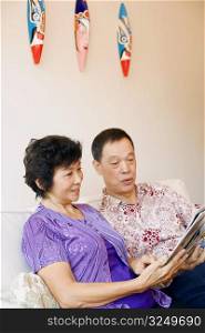 Close-up of a senior man and a mature woman reading a magazine
