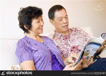 Close-up of a senior man and a mature woman reading a magazine