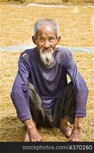 Close-up of a senior man crouching over rice grain, Zhigou, Shandong Province, China