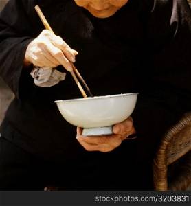 Close-up of a senior man eating with chopsticks, Xian, China