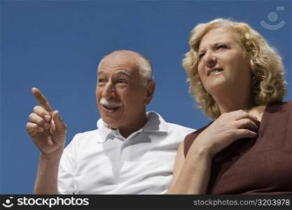 Close-up of a senior man gesturing beside a senior woman and smiling