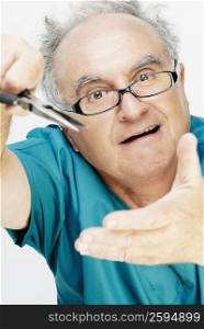 Close-up of a senior man holding a pair of pliers and making a face
