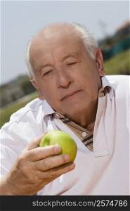 Close-up of a senior man holding an apple