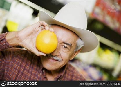 Close-up of a senior man holding an orange