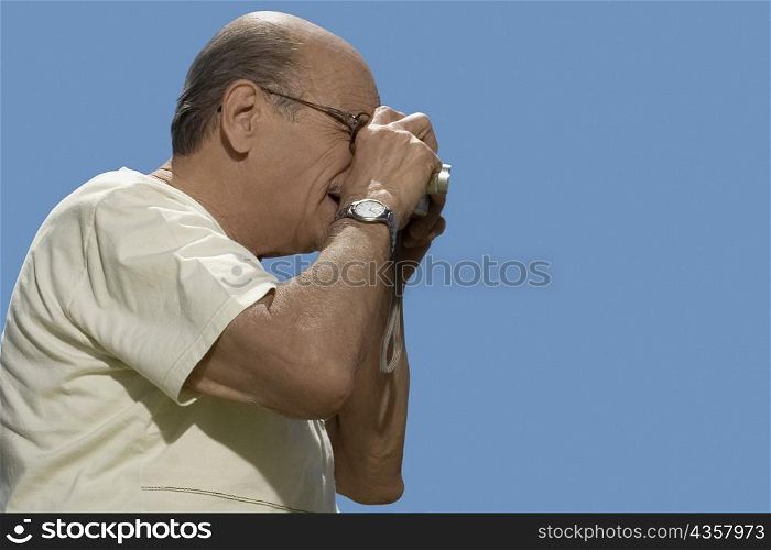 Close-up of a senior man photographing with a digital camera