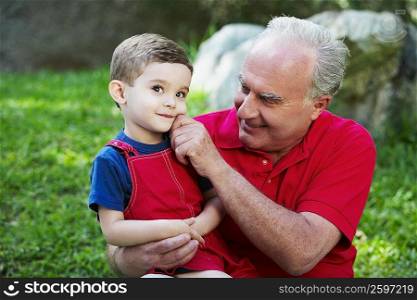 Close-up of a senior man pinching his grandson&acute;s cheek