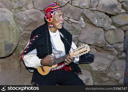 Close-up of a senior man playing a ukulele, Taquile Island, Lake Titicaca, Puno, Peru