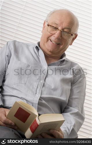 Close-up of a senior man reading a book and smiling